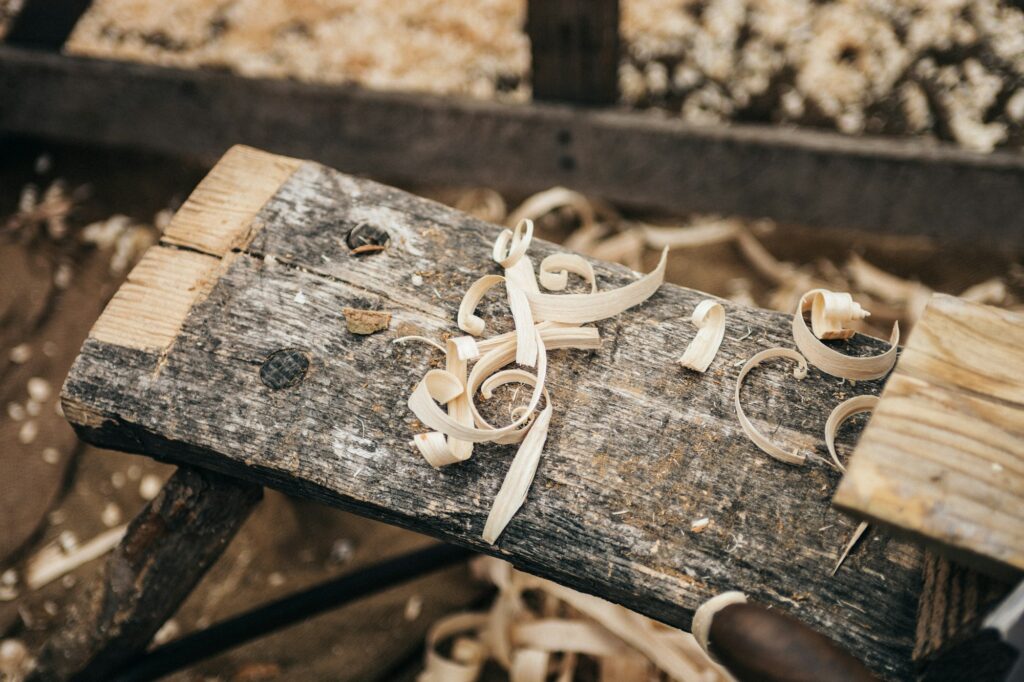 Curls of pale wood shavings on an old wooden workbench, sawdust scattered behind